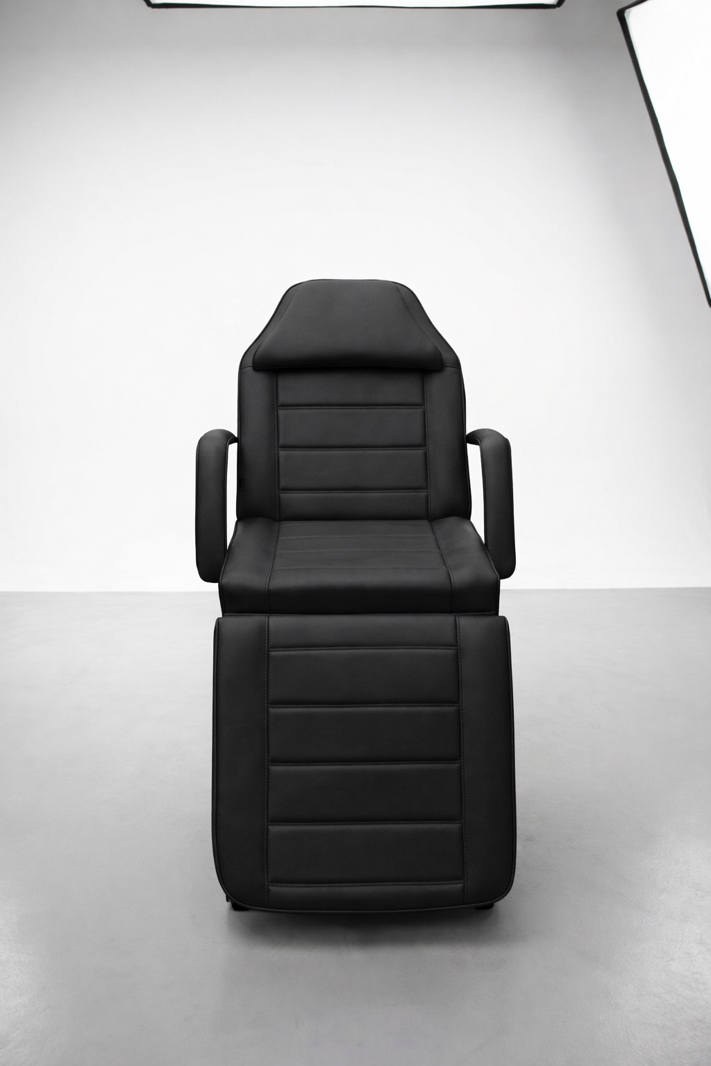 Versatile cosmetic treatment chair in black upholstery with reclining back and leg support for client comfort