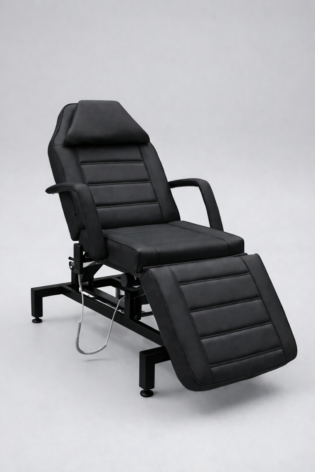 Commercial-grade beauty treatment bed in black vinyl with padded sections and adjustable back and leg positioning
