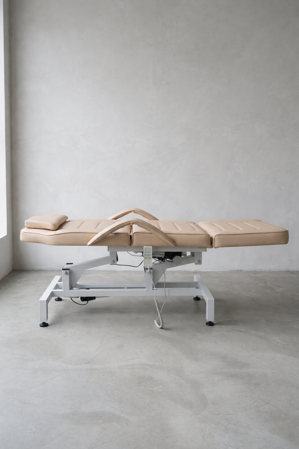Contemporary beauty bed in latte colour with reclining back and leg sections for versatile treatment applications