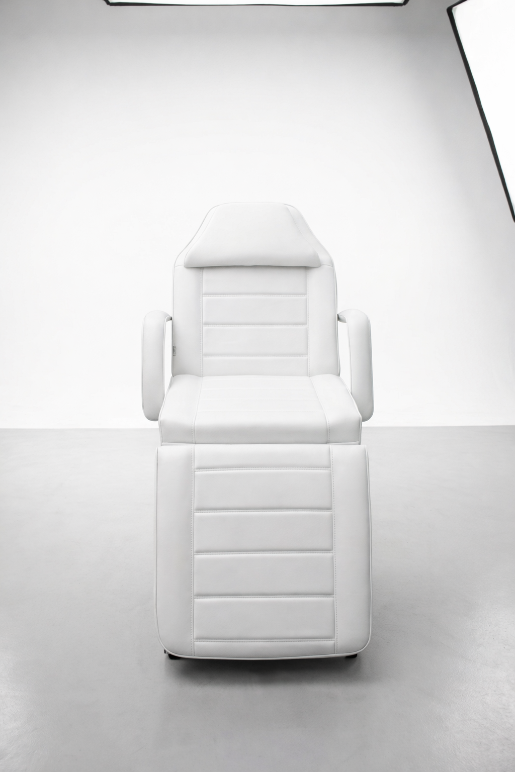 Contemporary clinic treatment bed in white finish with padded support and adjustable configuration for multiple services