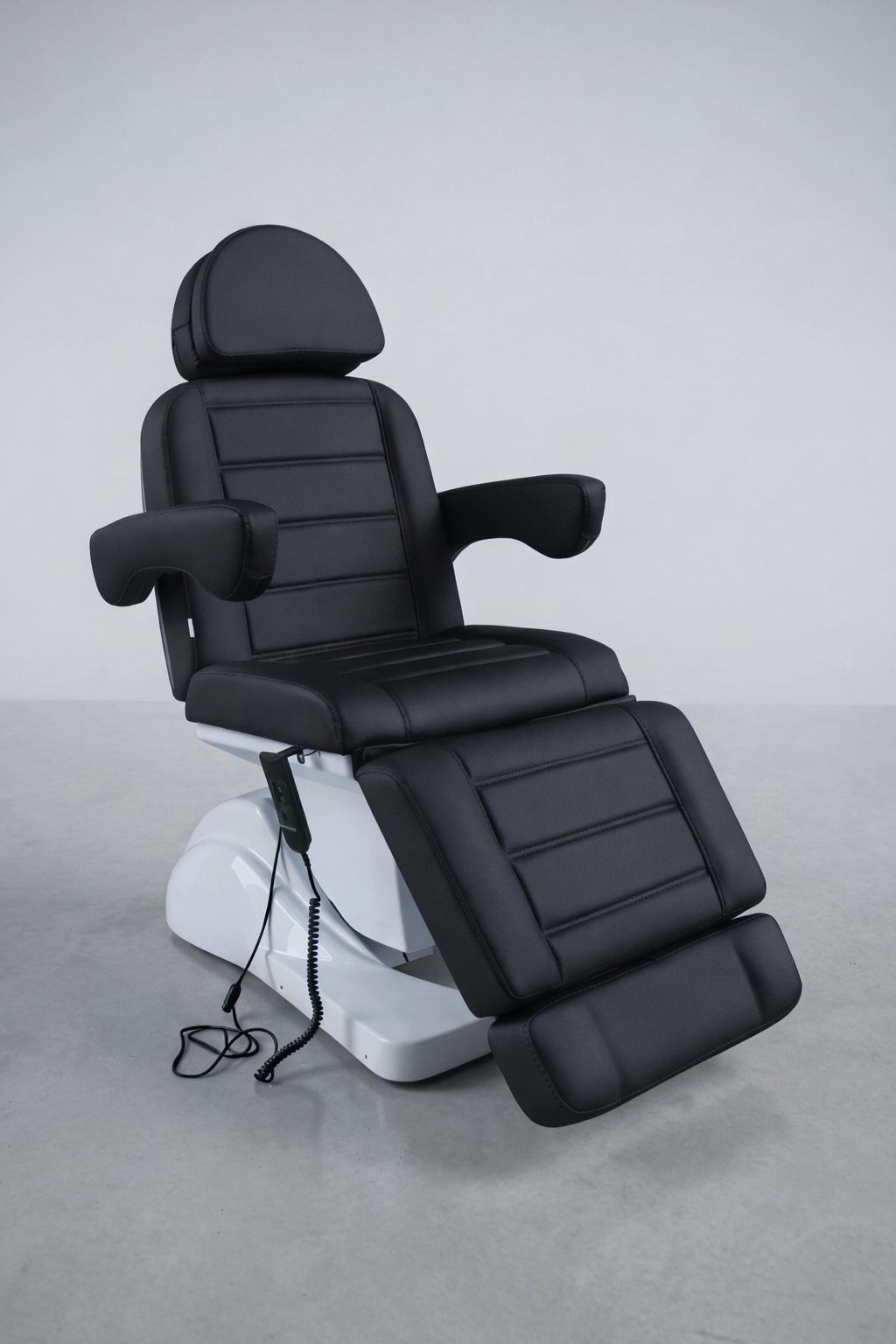 Sleek black vinyl treatment chair with motorised recline and segmented cushioning, ideal for clinics and beauty salons