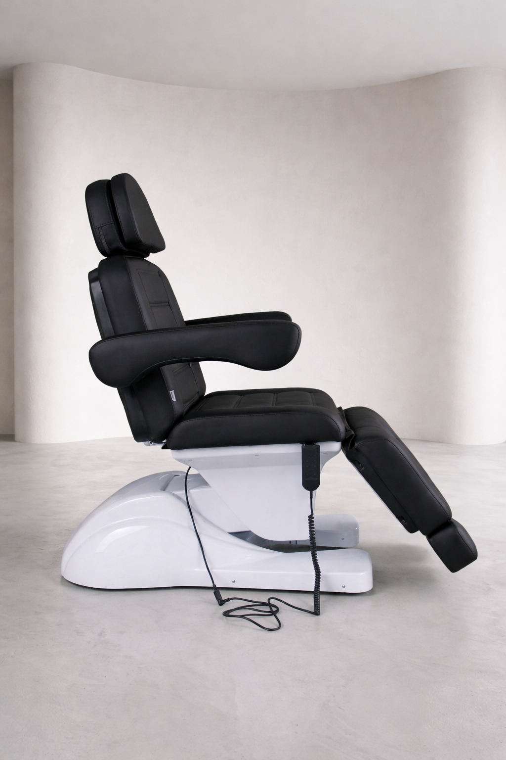 Professional facial bed in black upholstery with ergonomic armrests and adjustable sections for precision treatments