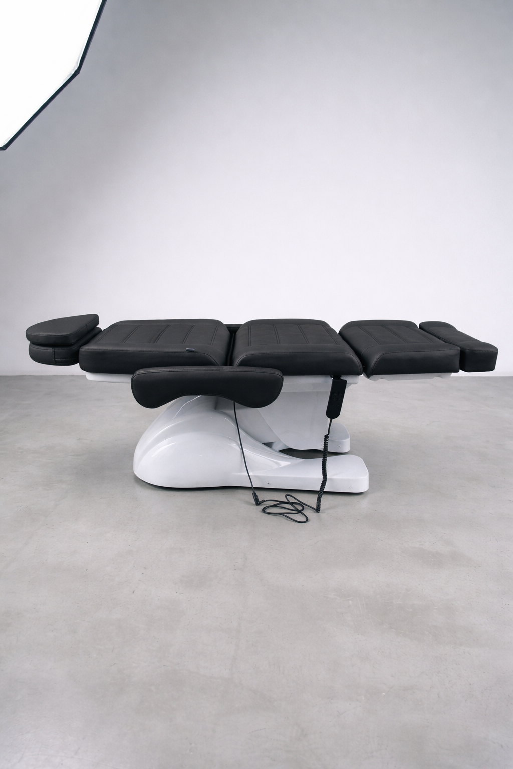 Commercial beauty treatment chair in black vinyl with powered height and recline, suitable for salons and medical spaces
