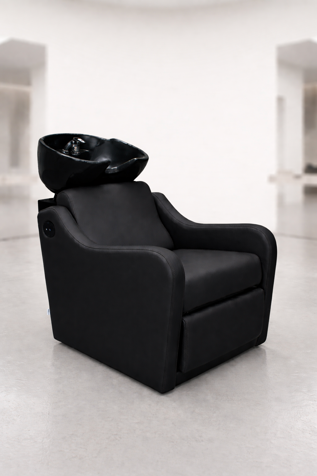 Professional shampoo basin chair in sleek black upholstery with padded armrests and integrated ceramic sink, salon wash station