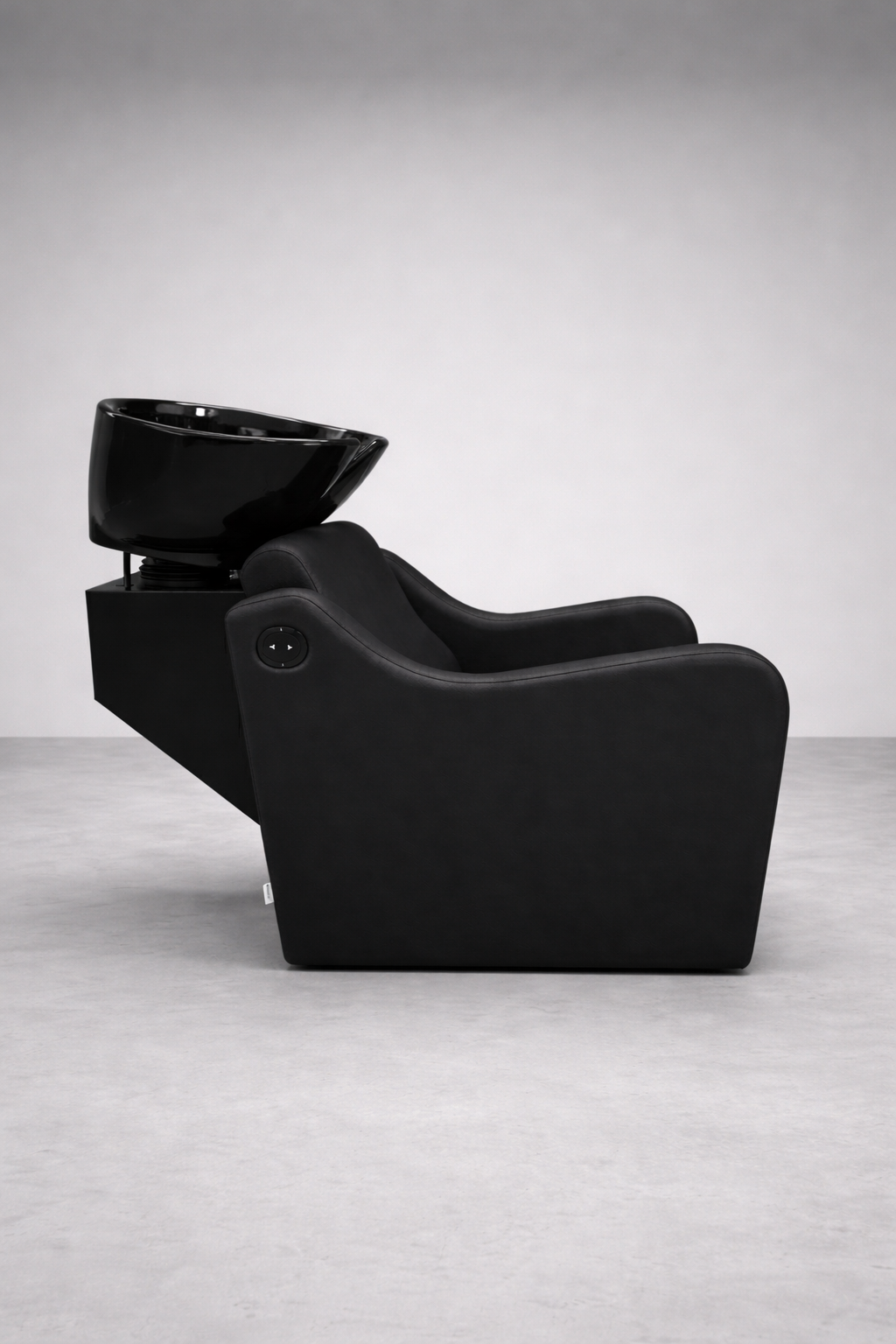 Contemporary salon backwash chair featuring black vinyl cushioning, ergonomic recliner, and glossy white basin for hair washing