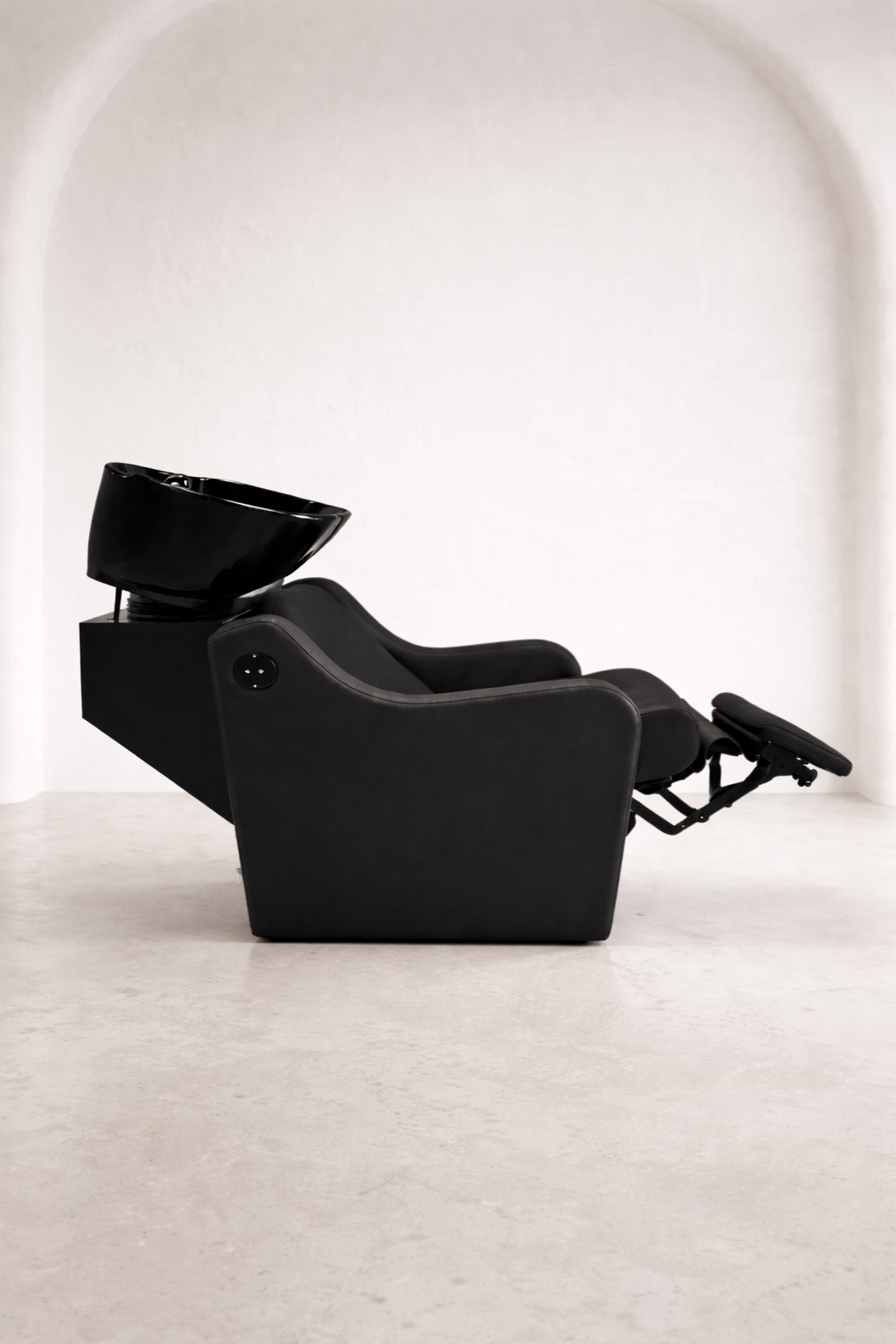 Premium hair salon shampoo unit with black upholstery, supportive armrests, and tilting ceramic basin for client comfort