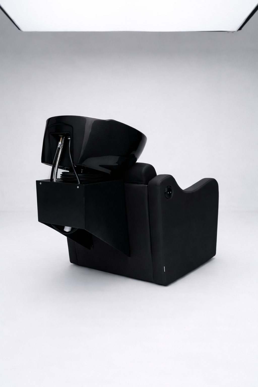 Ergonomic shampoo station chair in black vinyl with reclining backrest and ceramic basin, designed for professional salons
