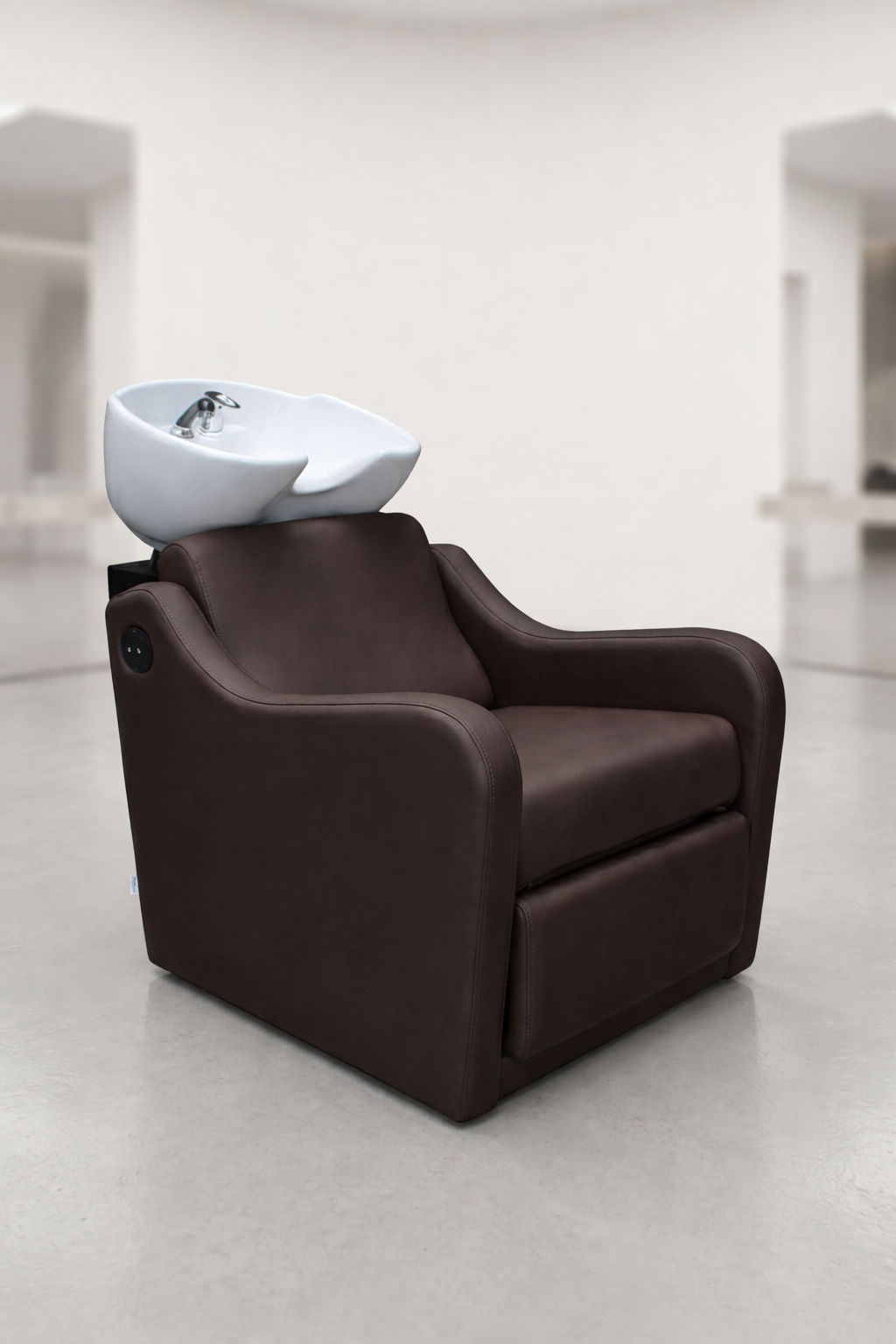 Professional shampoo basin chair in deep mocha brown upholstery with padded armrests and integrated ceramic sink, salon wash station