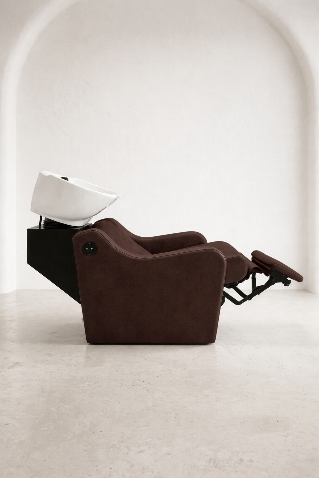 Premium hair salon shampoo unit with dark mocha upholstery, supportive armrests, and tilting ceramic basin for client comfort