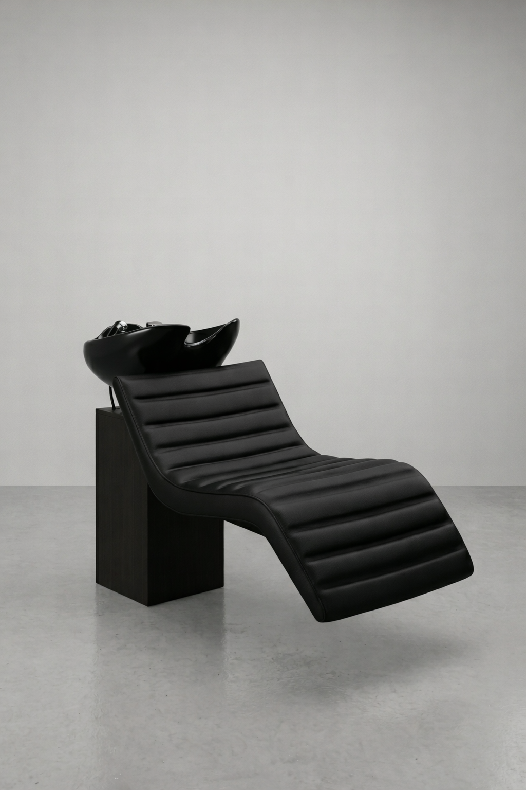 Black salon shampoo chair with ribbed vinyl recliner and ceramic basin, side profile on neutral studio background